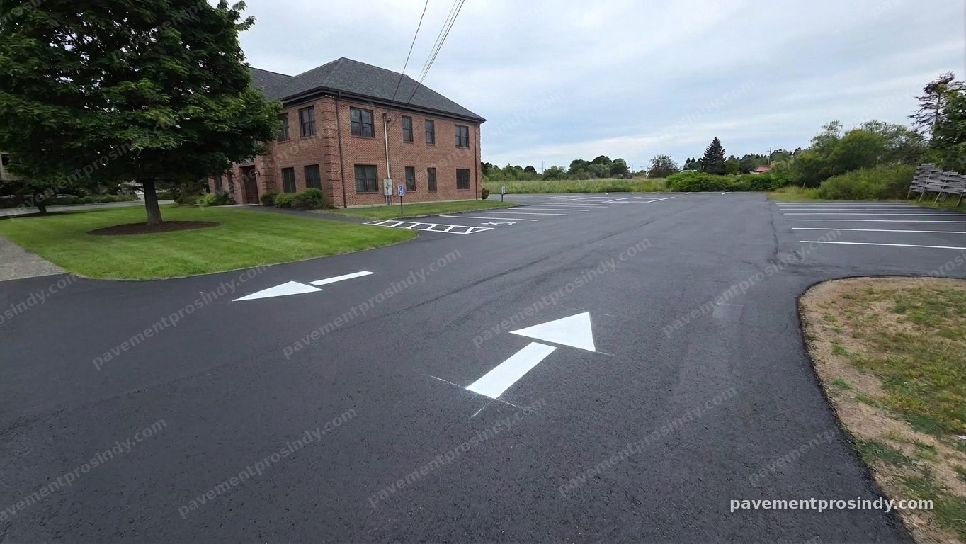 The same lot visualized after restriping — crisp white drive-lane arrows and freshly painted stall lines running the length of the lot, with the cones cleared away.